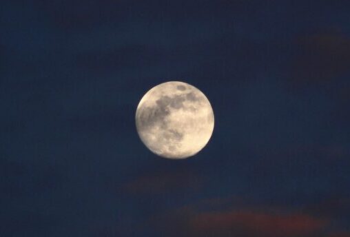 Beautiful full moon against a dark, cloudy night sky, offering a serene lunar view.