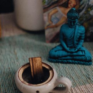 Tranquil setting with a blue Buddha figurine and incense for relaxation.