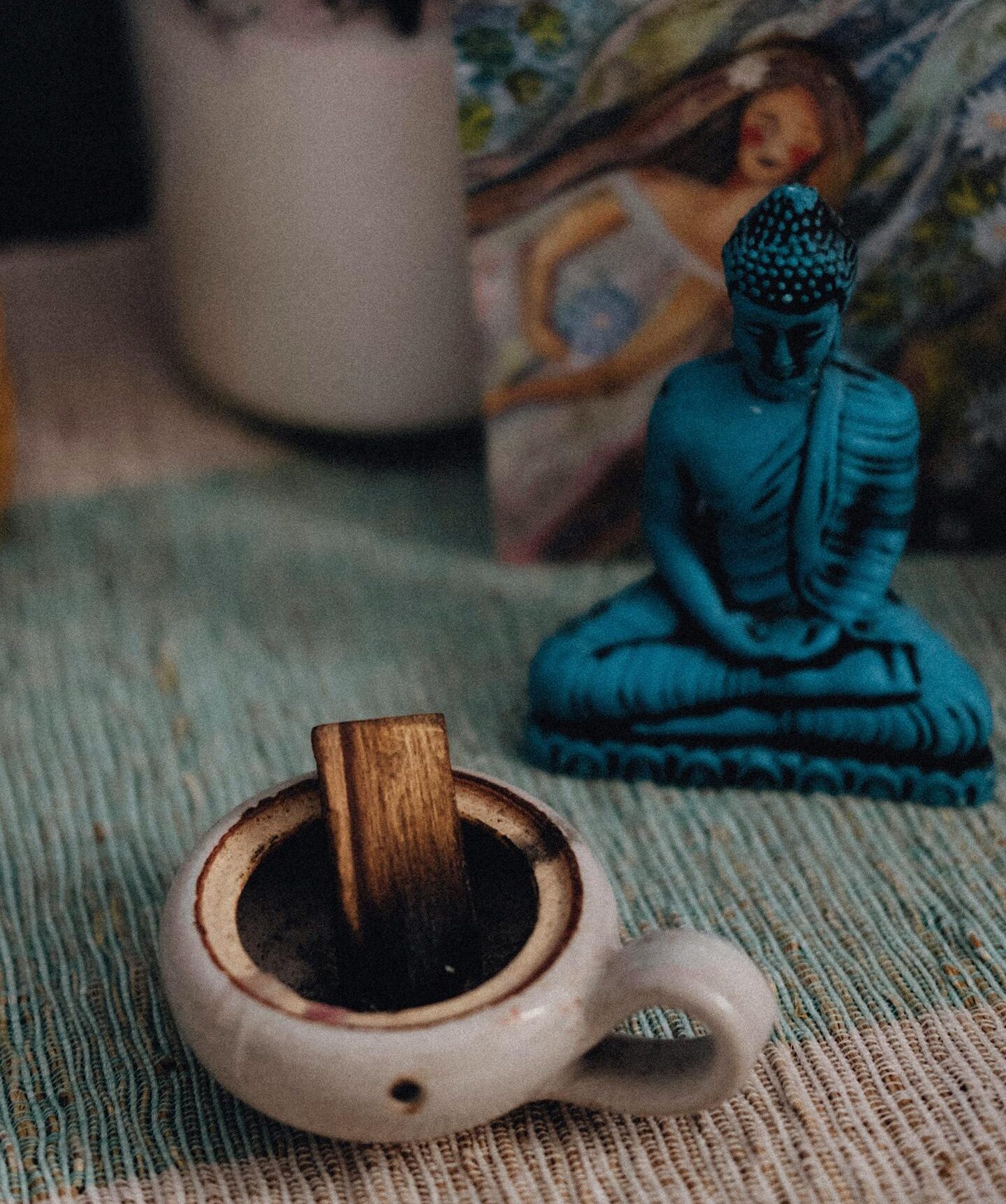 Tranquil setting with a blue Buddha figurine and incense for relaxation.